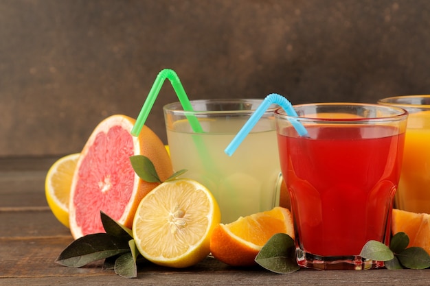 Jugos de cítricos. Limón, pomelo y jugo de naranja con frutas frescas en una mesa de madera marrón