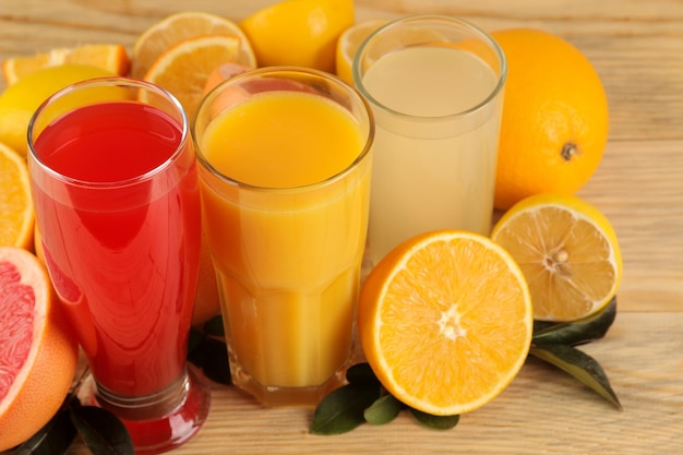 Jugos de cítricos. Zumo de naranja, limón y pomelo con frutas frescas sobre un fondo de madera natural.