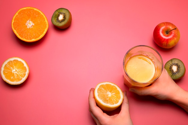 Jugos y frutas frescas saludables en el fondo rosa. Naranja, limón, kiwi, manzana. Espacio libre para texto. Lay Flat colorido. Concepto de nutrición o estilo de vida saludable.