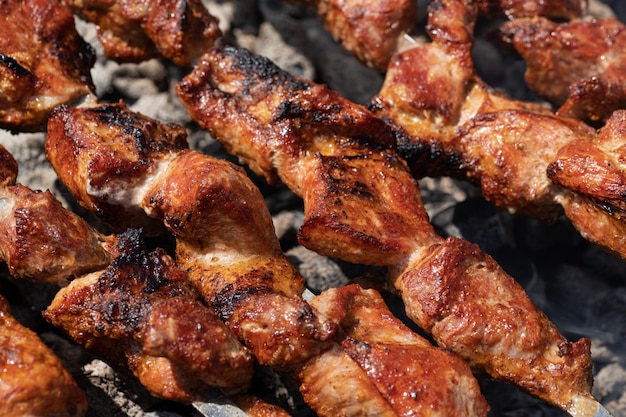 Jugosa barbacoa de cerdo cocinar en brochetas de metal en parrilla de carbón al aire libre