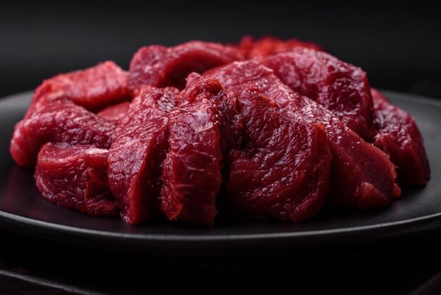 Jugosa carne cruda con especias, sal y hierbas sobre un fondo de hormigón oscuro