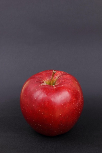 Jugosa manzana roja entera dulce sobre un fondo negro Concepto de comida saludable Primer plano de una fruta roja