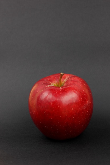 Jugosa manzana roja entera dulce sobre un fondo negro Concepto de comida saludable Primer plano de una fruta roja