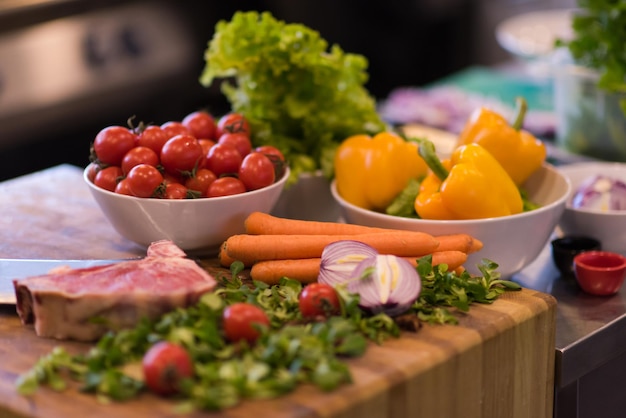 Jugosa rebanada de bistec crudo con verduras en una mesa de madera