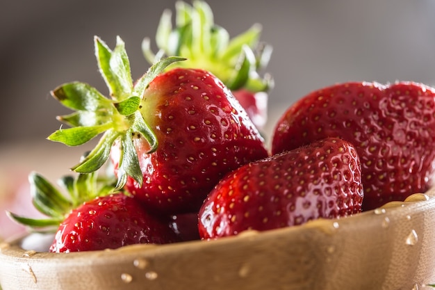 Jugosas fresas lavadas en un tazón de madera sobre la mesa de la cocina.