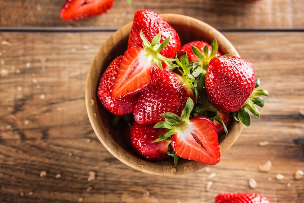 Jugosas fresas lavadas en un tazón de madera sobre la mesa de la cocina.