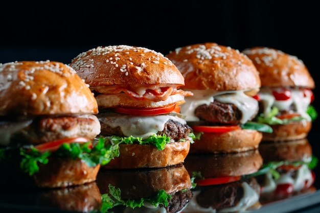 Jugosas hamburguesas de carne sobre un fondo negro.