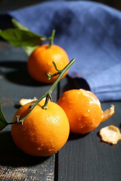 Jugosas mandarinas maduras con hojas sobre mesa de madera