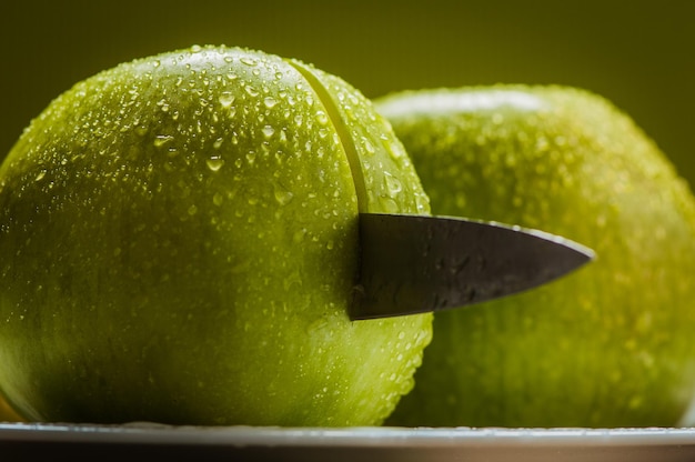 Jugosas manzanas amarillas frescas con gotas de agua en una navaja para cortar manzanas