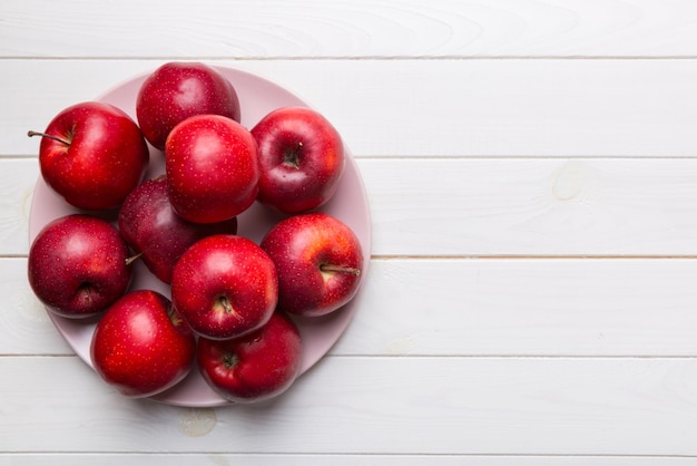 Jugosas manzanas rojas en un cuenco o plato en la vista de la mesa. Copia espacio