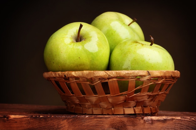 Jugosas manzanas verdes en canasta sobre mesa de madera