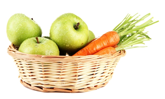 Jugosas manzanas verdes y zanahorias con hojas en canasta aisladas en blanco