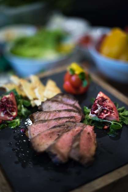 Jugosas rodajas de bistec a la parrilla con verduras sobre una tabla de madera