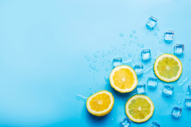 Jugosas rodajas de limón amarillo fresco y cubitos de hielo sobre un azul