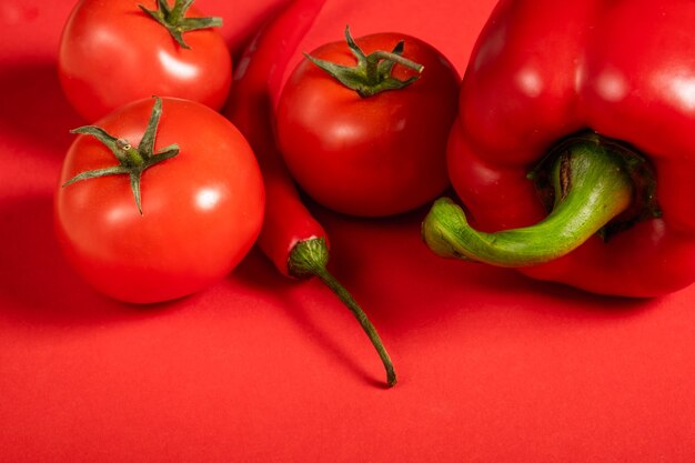 Jugosas verduras rojas tomates y chiles y pimientos sobre una superficie de color rojo brillante