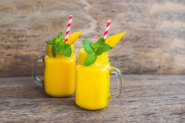 Jugoso batido de mango en vasos con paja rayada