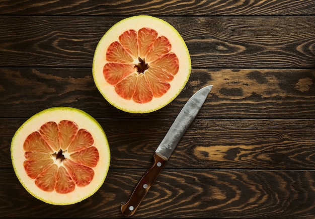 Foto jugoso pomelo rojo maduro cortado por la mitad se encuentra en la mesa de madera