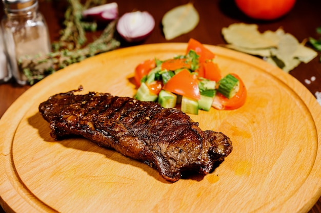 Un jugoso trozo de carne frita se encuentra en una tabla de cortar contra una mesa de madera.