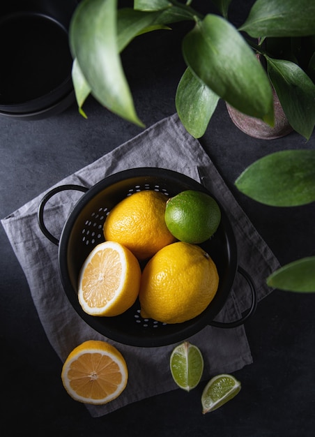Jugosos limones y limas en un recipiente negro sobre una mesa gris Vista superior