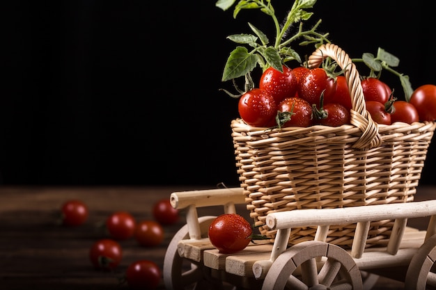 Jugosos tomates rojos en la cesta en la mesa de madera