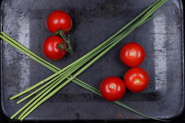 Jugosos tomates rojos dulces y ramitas verdes sobre un fondo negro Concepto de comida saludable Primer plano