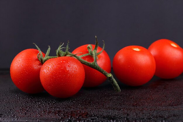 Jugosos tomates rojos dulces sobre un fondo negro Concepto de comida saludable Primer plano