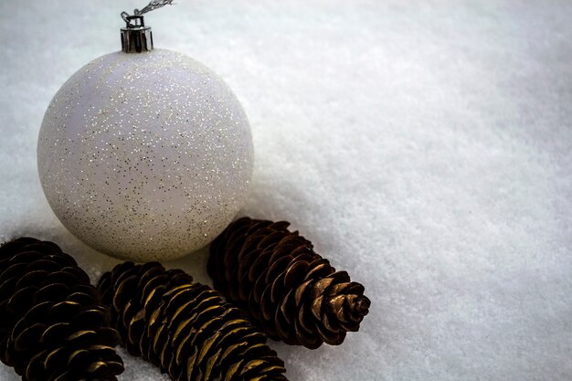 Juguete de año nuevo y conos se encuentran en la nieve.