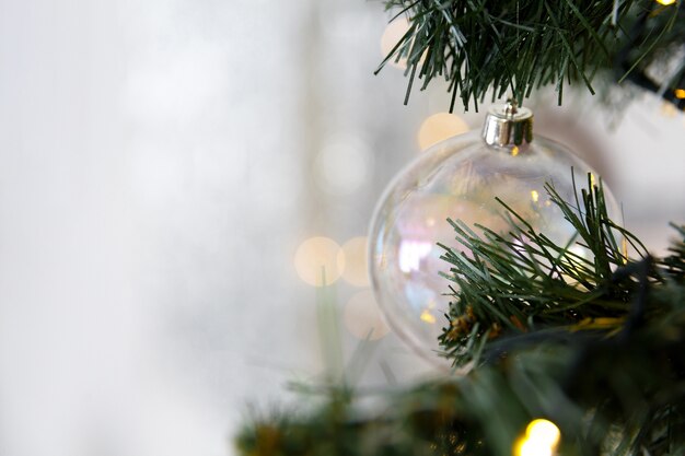 Juguete del árbol de Navidad, bola de cristal transparente en la rama con guirnaldas de luces bokeh