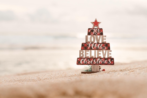 Foto juguete de árbol de navidad de madera en la playa