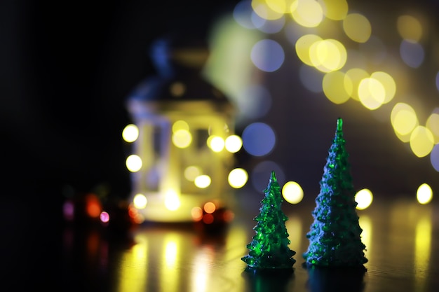 Juguete de árbol de Navidad rojo en una rama de un abeto natural con luces de guirnaldas en desenfoque en el fondo. Juguete de metal con ranuras de ciervo y copos de nieve. Navidad, año nuevo, espacio de copia, bokeh.