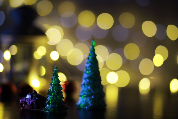 Juguete de árbol de Navidad rojo en una rama de un abeto natural con luces de guirnaldas en desenfoque en el fondo. Juguete de metal con ranuras de ciervo y copos de nieve. Navidad, año nuevo, espacio de copia, bokeh.