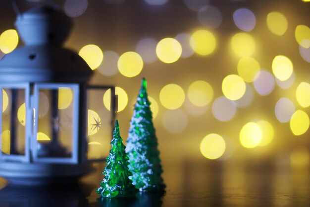 Juguete de árbol de Navidad rojo en una rama de un abeto natural con luces de guirnaldas en desenfoque en el fondo. Juguete de metal con ranuras de ciervo y copos de nieve. Navidad, año nuevo, espacio de copia, bokeh.