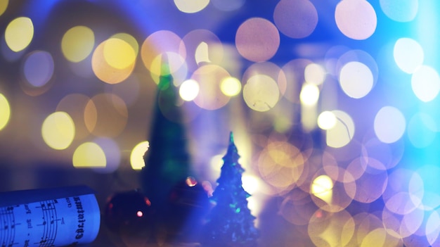 Juguete de árbol de Navidad rojo en una rama de un abeto natural con luces de guirnaldas en desenfoque en el fondo. Juguete de metal con ranuras de ciervo y copos de nieve. Navidad, año nuevo, espacio de copia, bokeh.