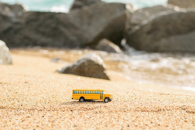 Juguete de autobús escolar antiguo en la arena de la playa