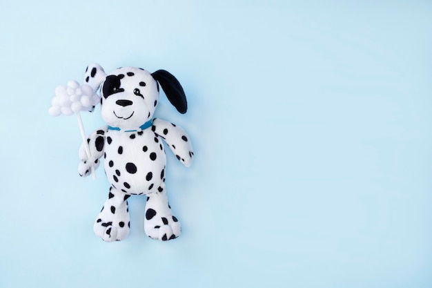 Juguete cachorro dálmata sosteniendo una pequeña nube sobre fondo azul claro