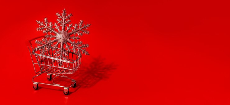 Foto juguete de carro de compras con juguetes de navidad y pared roja. copie el espacio. descuentos, rebajas. venta de navidad y año nuevo.