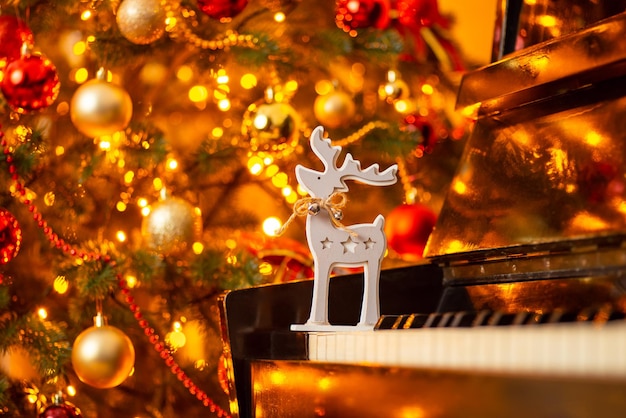 Juguete de ciervo de madera en el piano brillante árbol de Navidad decorado en el fondo