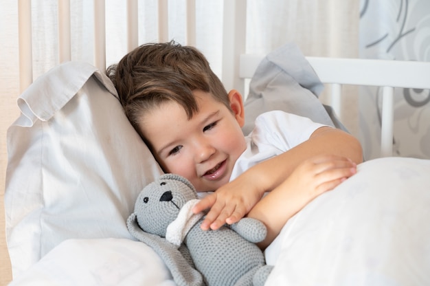 Juguete de conejo en manos de los niños. Sueño reparador en un abrazo con un juguete.