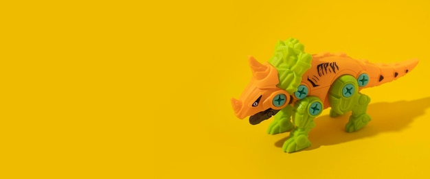 Juguete de dinosaurio de plástico sobre fondo amarillo Banner