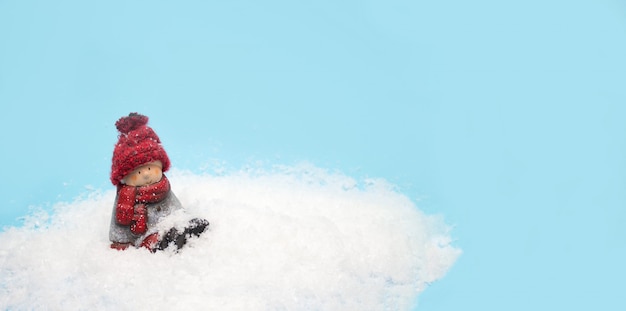 Juguete de duende navideño se sienta en la nieve, banner para encabezado de sitio web