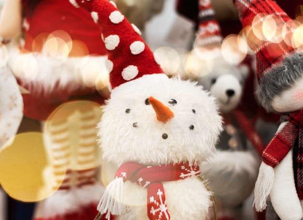 Juguete hermoso muñeco de nieve de cerca. Juguetes navideños esponjosos. Juguete de muñeco de nieve sonriente en un sombrero rojo de cerca.