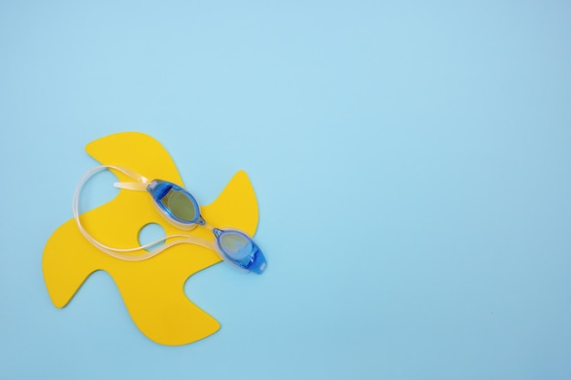 Foto juguete para jugar a escribir y gafas para nadar en un espacio de copia de vacaciones de verano de fondo azul