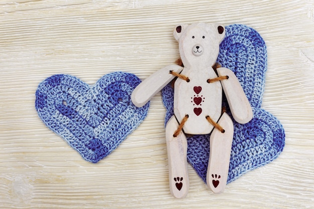 Juguete de madera con corazón de punto azul. Toy Bear de madera blanco hecho a mano en el fondo de madera blanco.