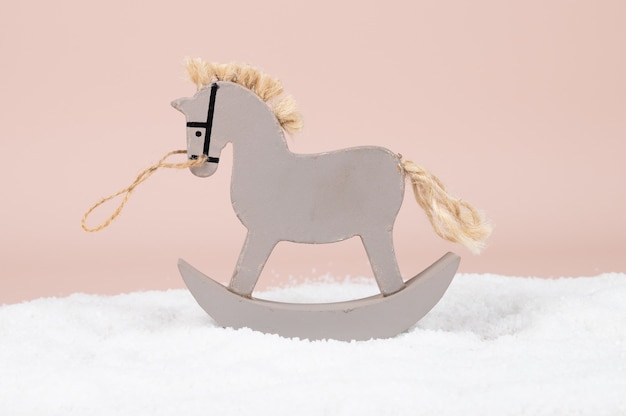 Juguete de madera mecedora caballo gris sobre fondo de nieve. Foto de alta calidad