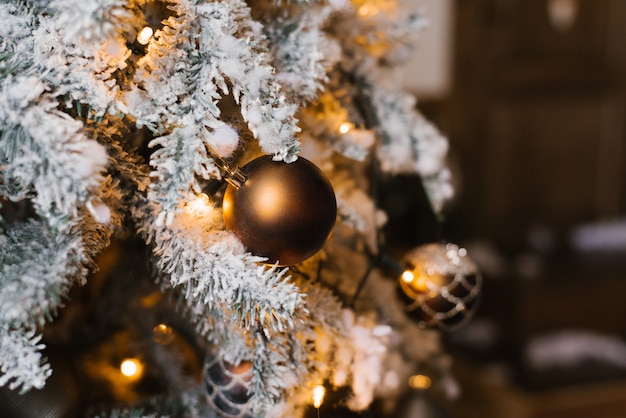 Juguete marrón bola de Navidad en el árbol de Navidad con luces