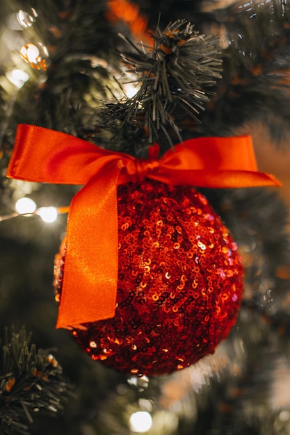 Juguete de Navidad con arco de seda rojo colgado en el árbol de Navidad Detalles mágicos con luces bokeh