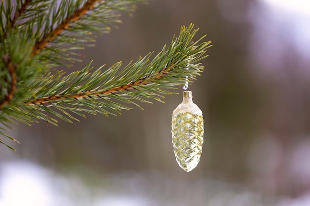 Juguete navideño en forma de cono colgado de un árbol de Navidad en la naturaleza