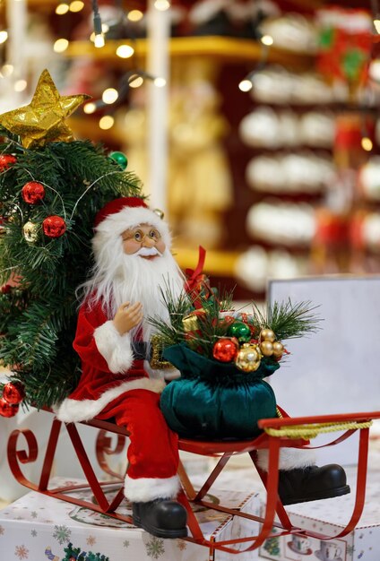 Foto juguete de papá noel con barba sentado en un trineo bokeh fondo trineo de navidad con bolsa trineo saco regalos de navidad juguetes árboles brillantes juguetes presentes y regalos de año nuevo santa se apresura a entregar regalos