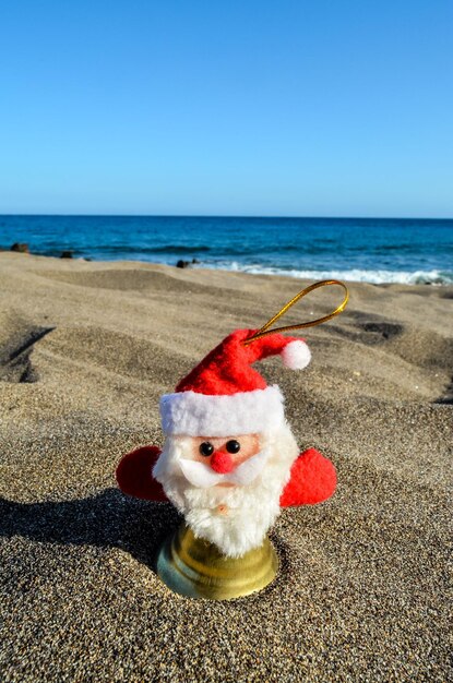 Foto juguete de papá noel en la playa de arena