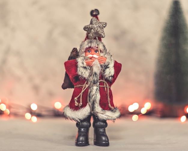 El juguete de Papá Noel sostiene un bastón con una estrella y un árbol de Navidad en un fondo